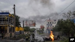 11 جولائی 2022 کو یوکرائن کے شہر خارکیو کے ایک رہائشی محلے میں روسی حملے کے بعد امدادی کارکنوں نے تباہ شدہ کار کی آگ بجھا دی۔
