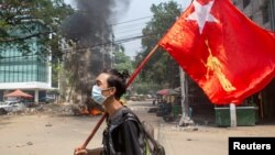 میانمار میں فوجی بغاوت کے خلاف احتجاج کے دوران ایک شخص نیشنل لیگ فور ڈیموکریسی کا پرچم تھامے ہوئے (فائل فوٹو)